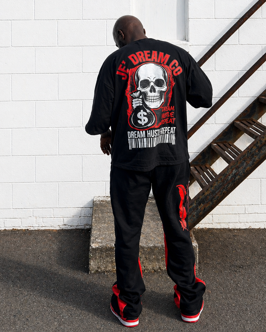 Back of Black graphic streetwear shirt by Je’ Dream Co featuring “Turn Your Pain Into Hustle” slogan, bold skull biker design, red flame backdrop, oversized fit, and premium cotton fabric for edgy urban fashion and motivational style on a model