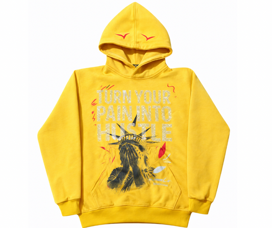 Yellow hoodie with turn your pain into hustle text in rhinestones and Statue of Liberty shame face, feather design on a white background