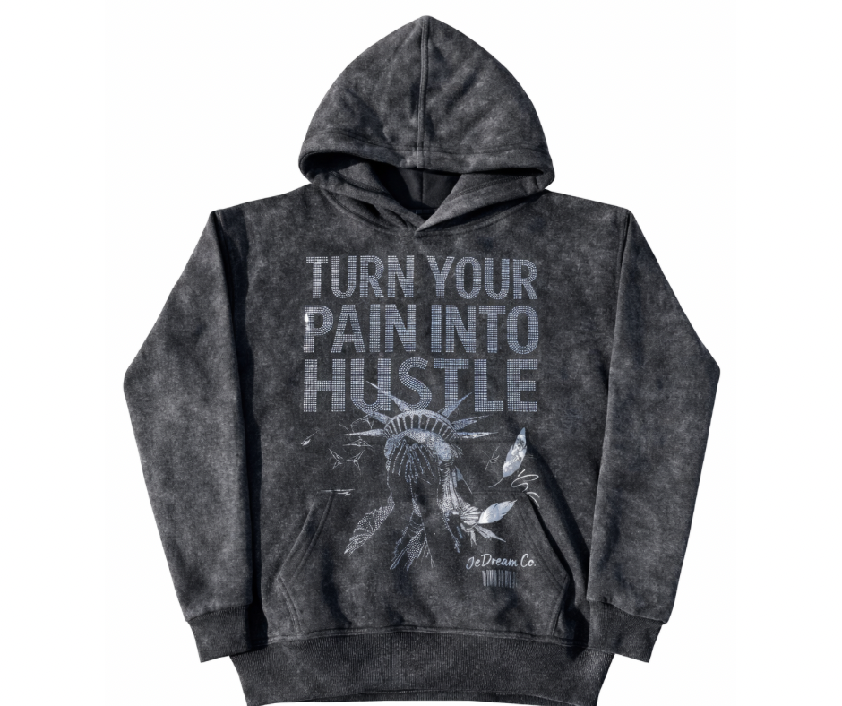 Black acid wash hoodie with 'Turn Your Pain into Hustle' text in rhinestones and shame face of Statue of Liberty graphic on a white background
