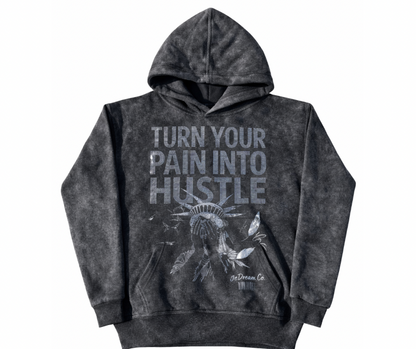 Black acid wash hoodie with 'Turn Your Pain into Hustle' text in rhinestones and shame face of Statue of Liberty graphic on a white background