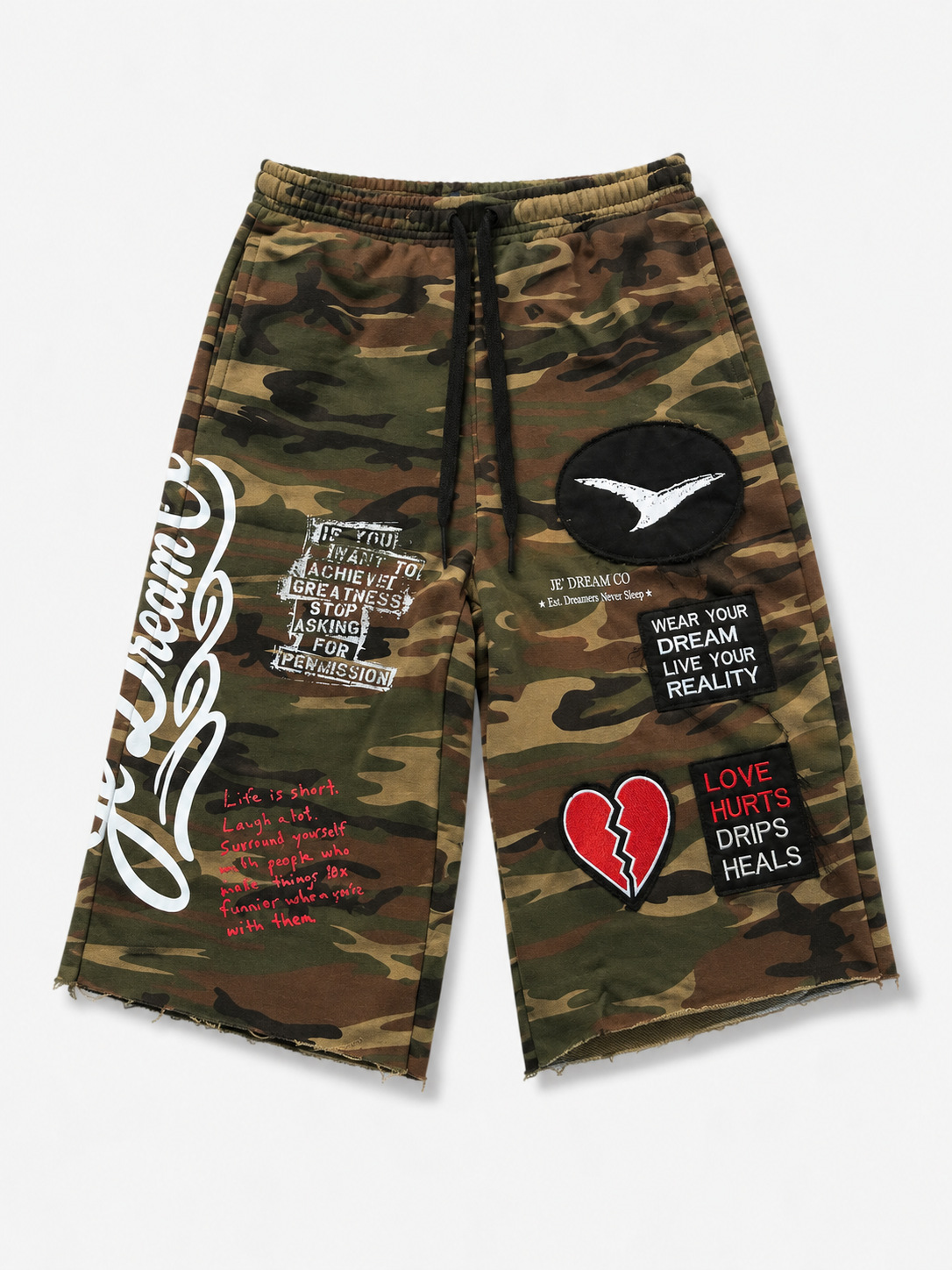 A pair of camouflage print shorts with a black drawstring waist, featuring various graphic patches and text prints including je’ Dream co a broken heart patch, and motivational quotes.