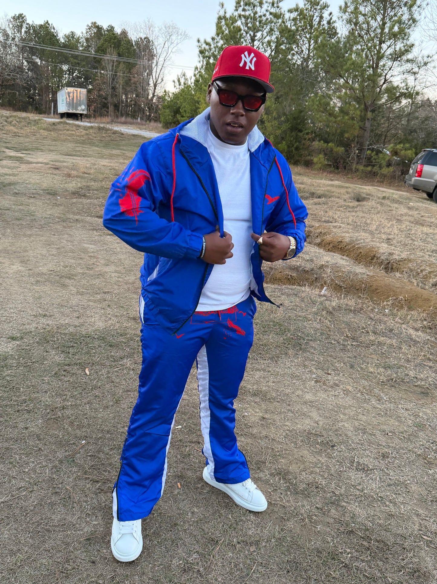 Person wearing a blue windbreaker with red accents on a dirt road.